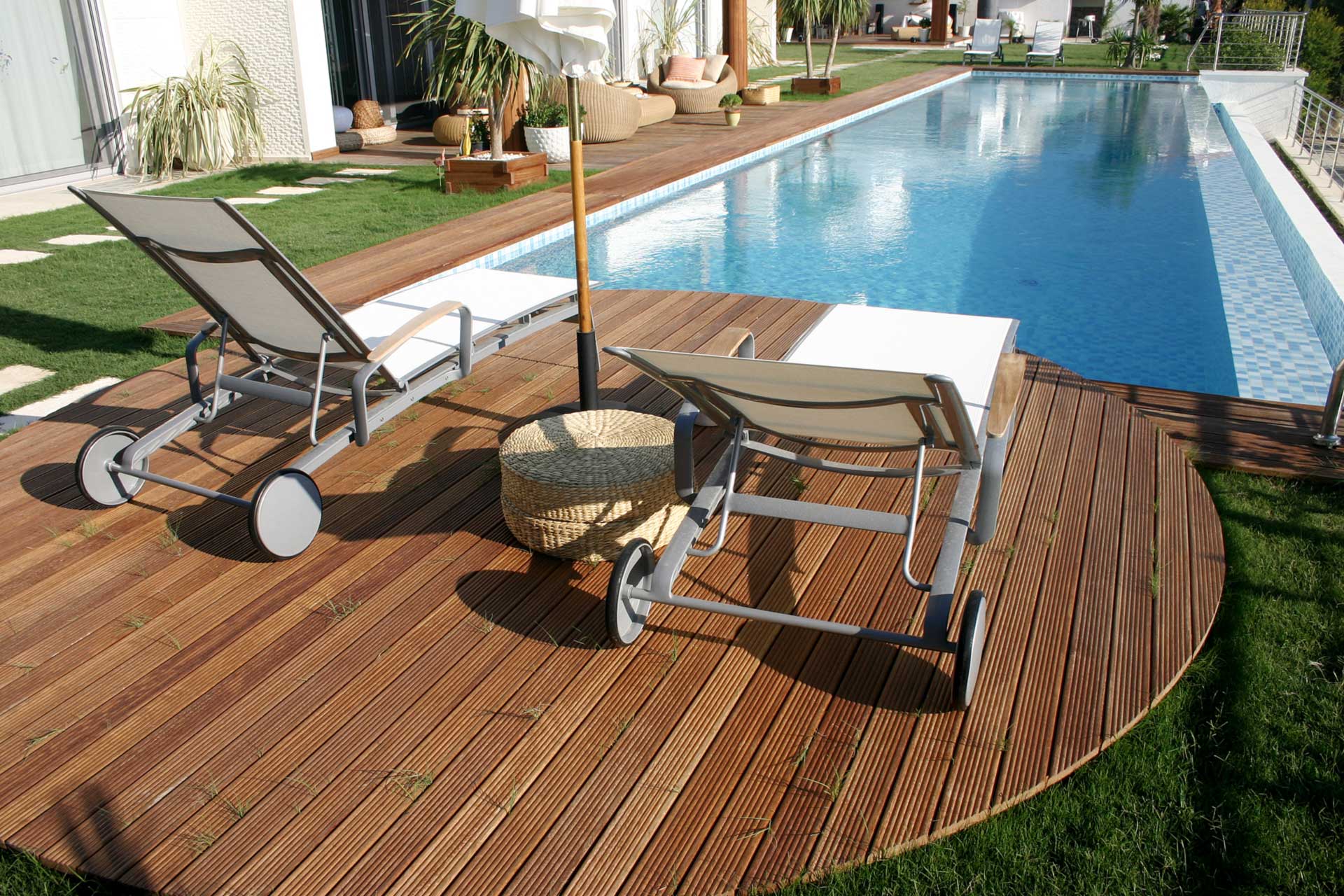 Holzterrasse mit Liegestühlen rund um einen Außenpool