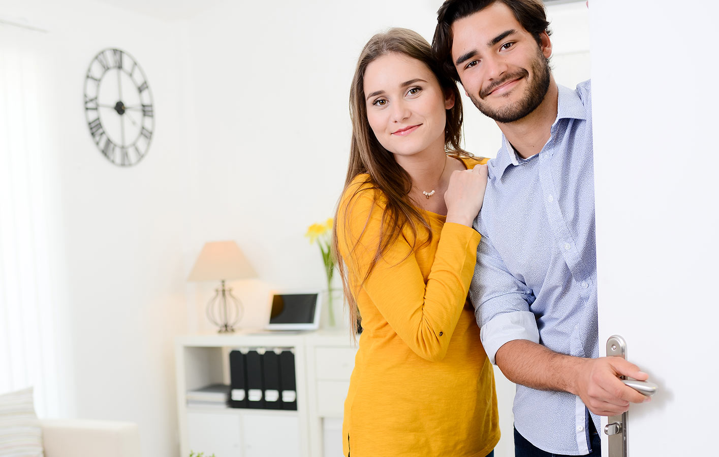 Mann und Frau öffnen die weiße Zimmertür. Blick in das Wohnzimmer