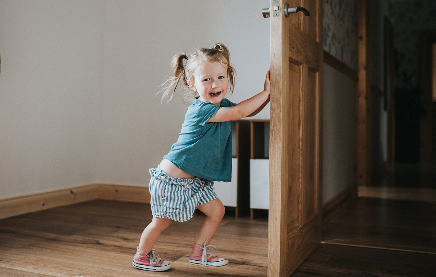 Kind schließt eine Zimmertür aus Holz